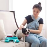 A woman pets her dog on a couch.